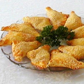 Golden cheese burekas triangles, hot from the oven and sprinkled with sesame seeds